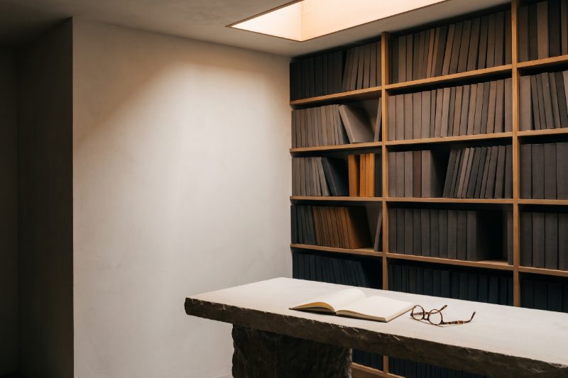 A quiet office library with shelves of bound reports and a reading table under a skylight